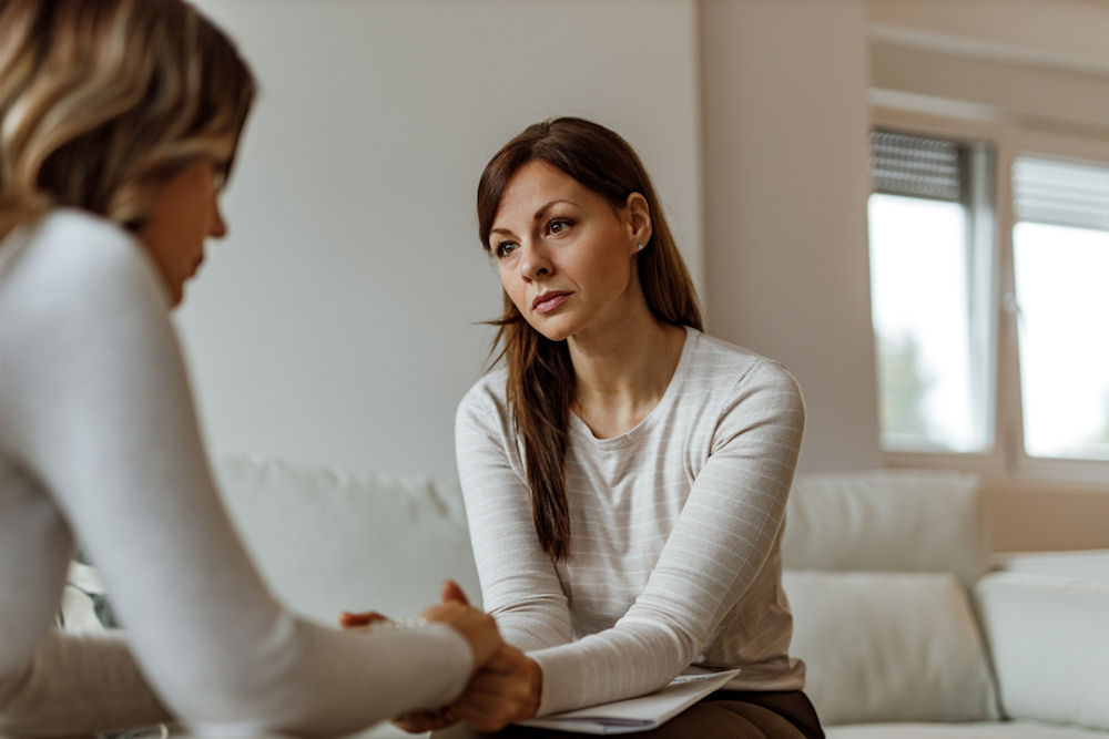 two women holding hands in therapy